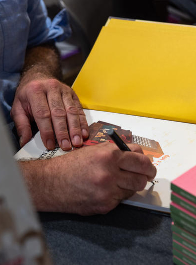 vue serree sur un dessinateur signant une bande dessinee